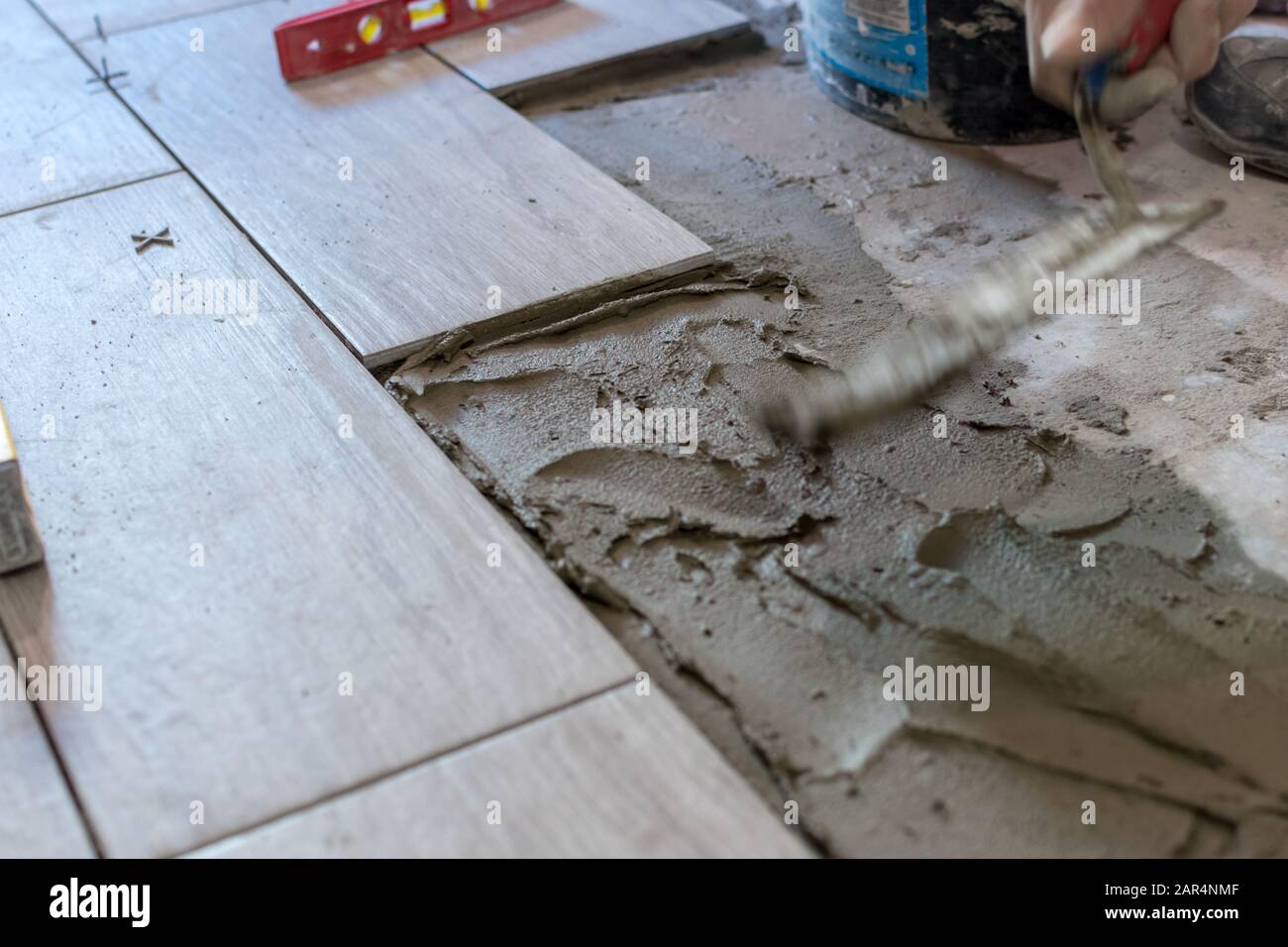 Man installing rectangular shaped floor tiles in kitchen. Applying ...