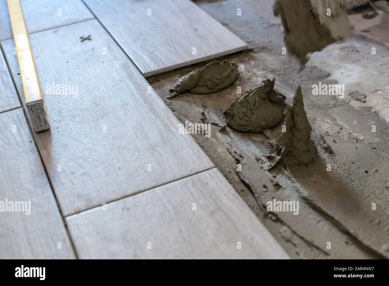 Man installing rectangular shaped floor tiles in kitchen. Applying ...
