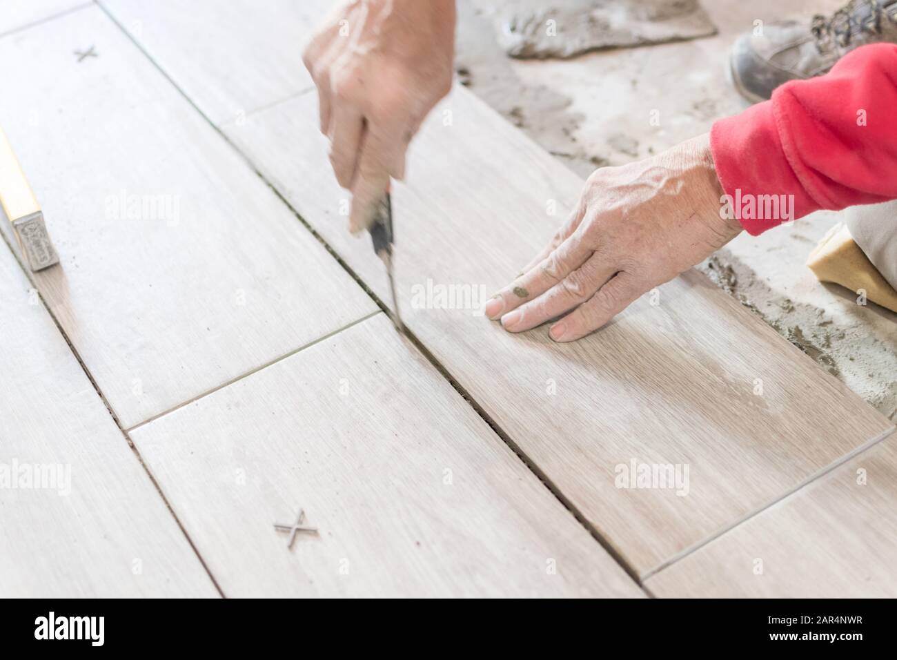 Man installing rectangular shaped floor tiles in kitchen. Applying ...