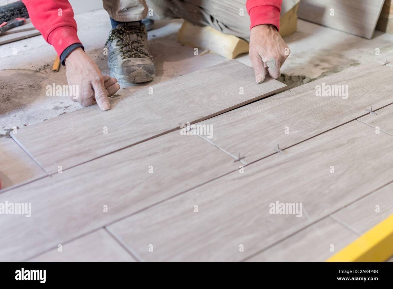 Man installing rectangular shaped floor tiles in kitchen. Applying ...