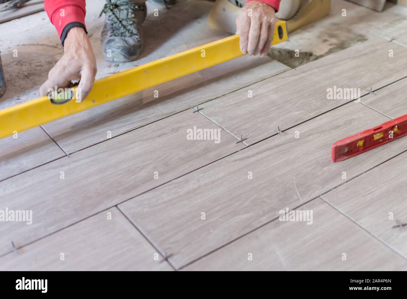 Man installing rectangular shaped floor tiles in kitchen. Applying ...