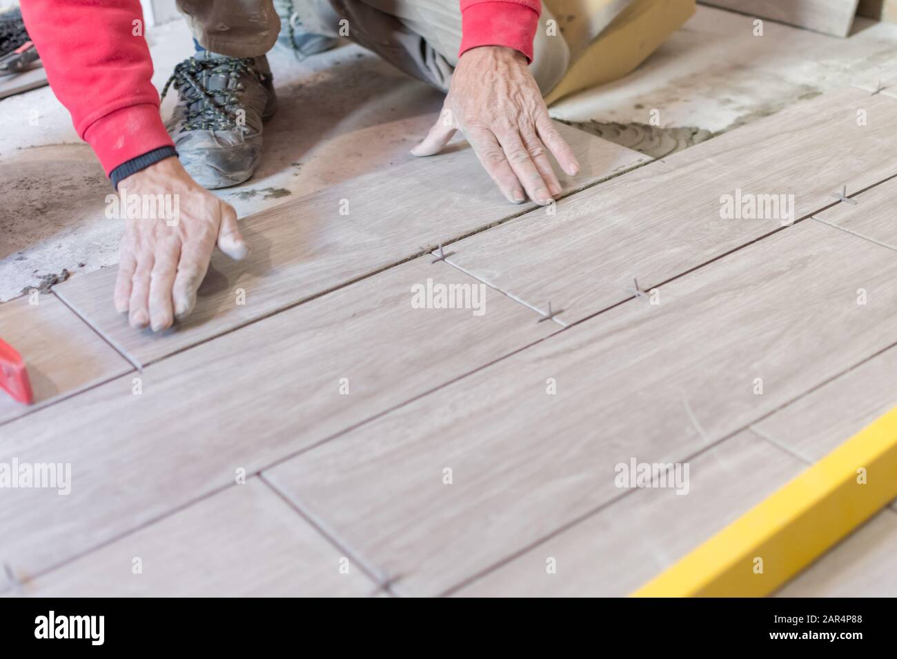 Man installing rectangular shaped floor tiles in kitchen. Applying ...