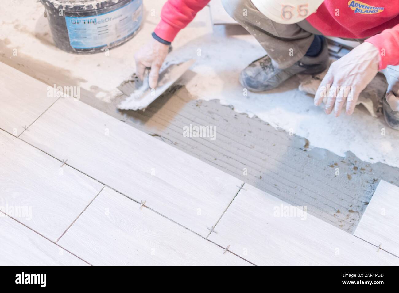 Man installing rectangular shaped floor tiles in kitchen. Applying ...