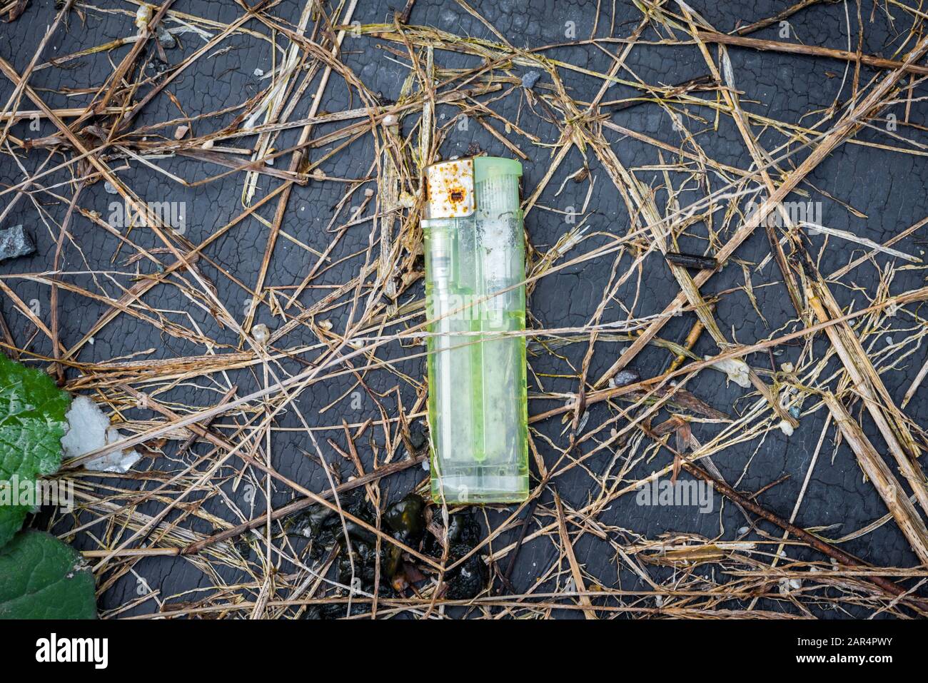 Old, rusty and green lighter thrown on the ground. Stock Photo