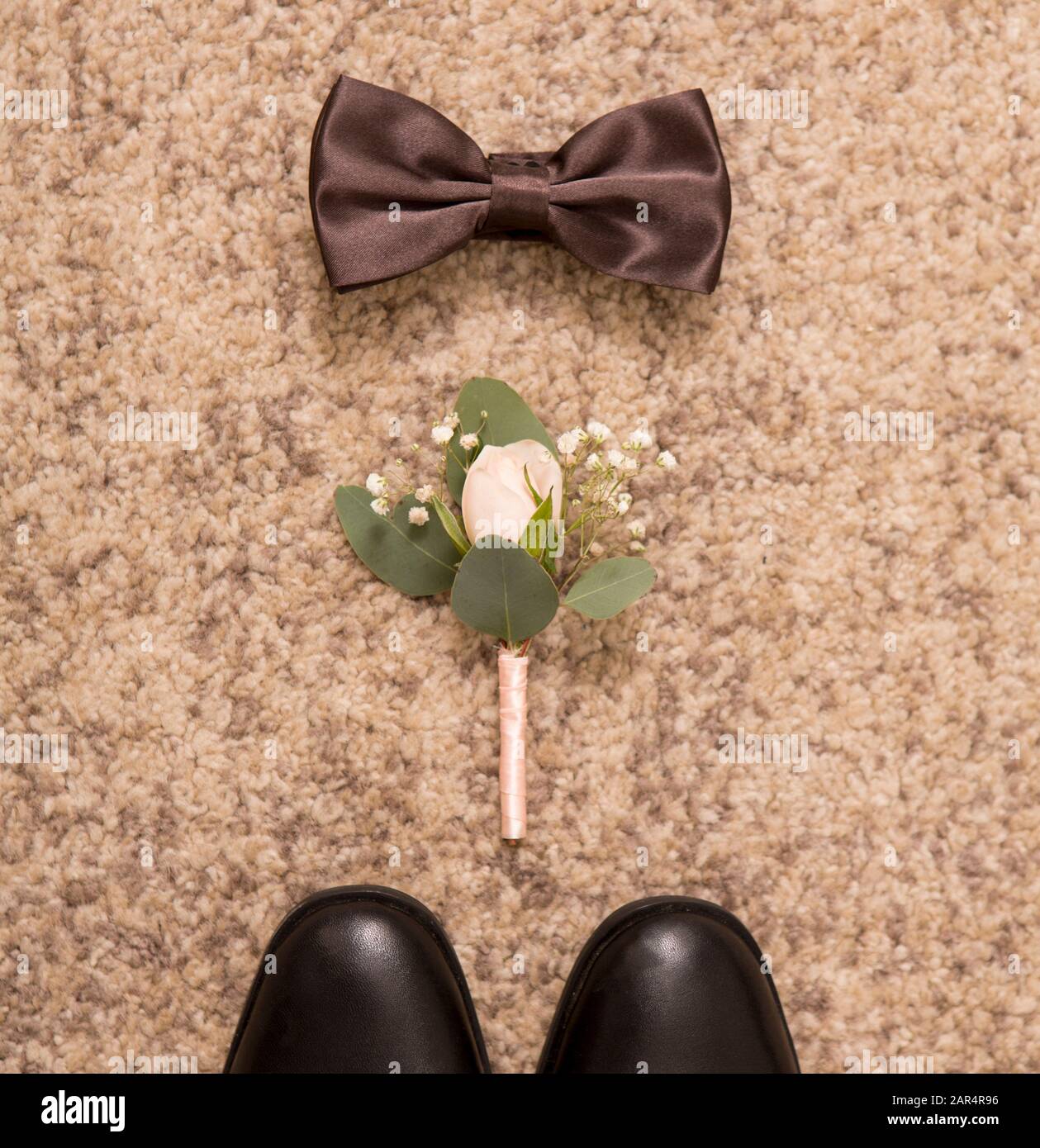 Black shoes, boutonniere and bow tie on floor background Stock Photo