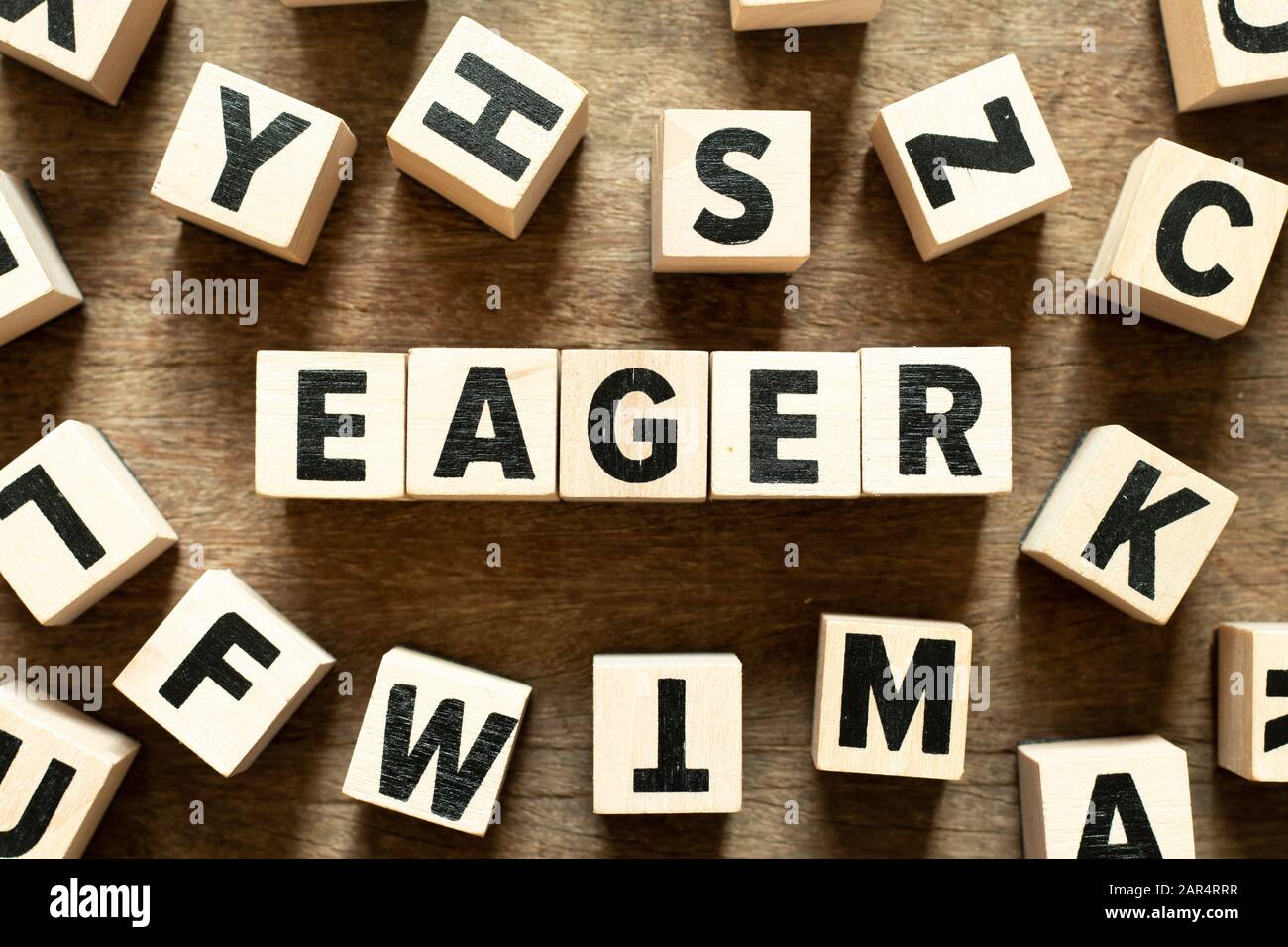 Letter block in word eager with another block on wood background Stock