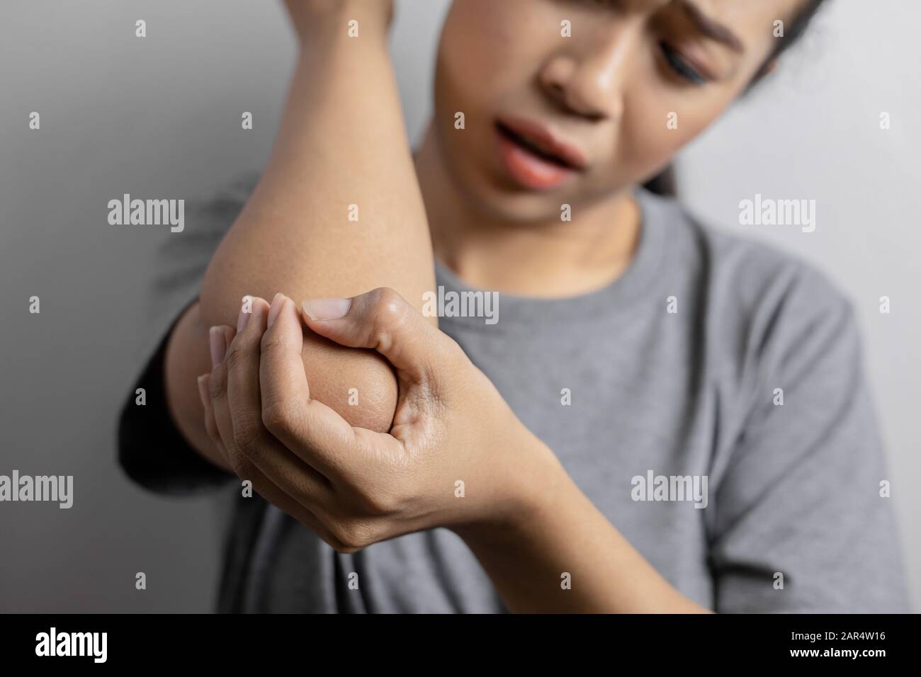 Women with pain in elbow. Acute pain in a elbow. Young woman holds on to elbow. Stock Photo