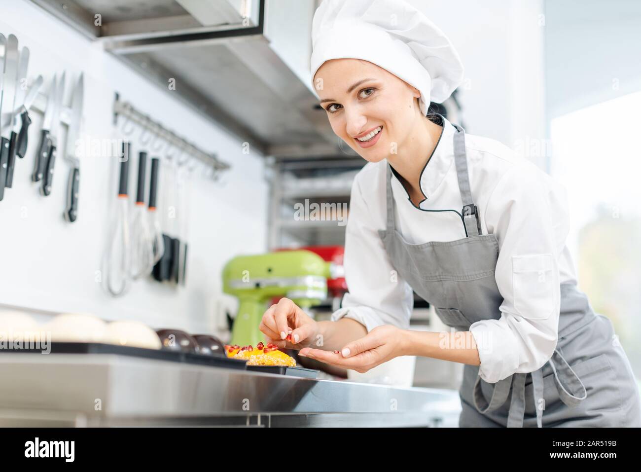 Pastry chef putting cranberries on top of little tartelettes Stock Photo