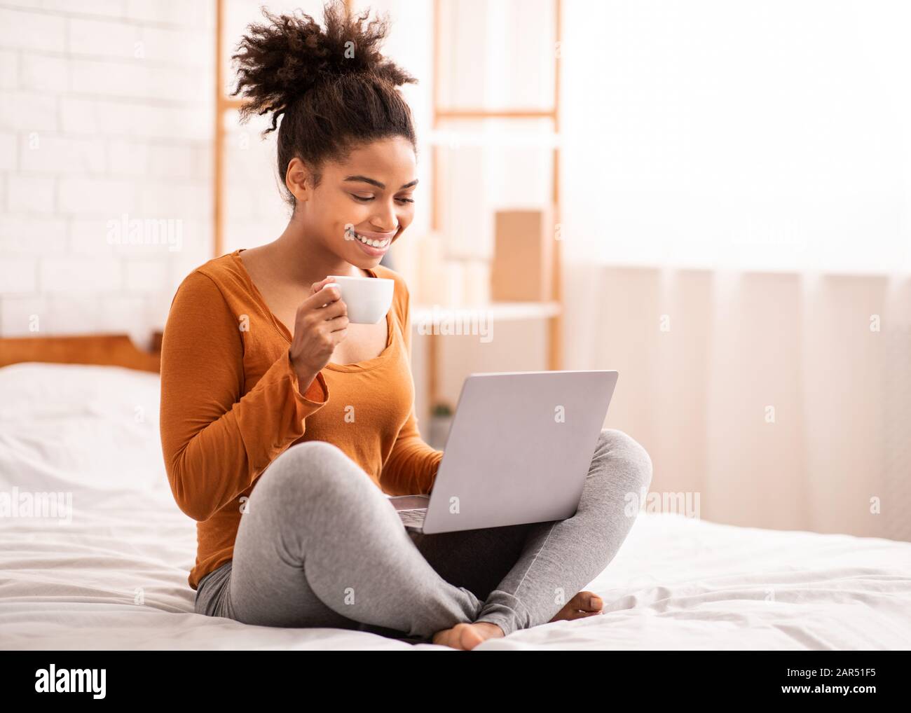 African American Girl Using Laptop Having Coffee Sitting In Bed Stock ...