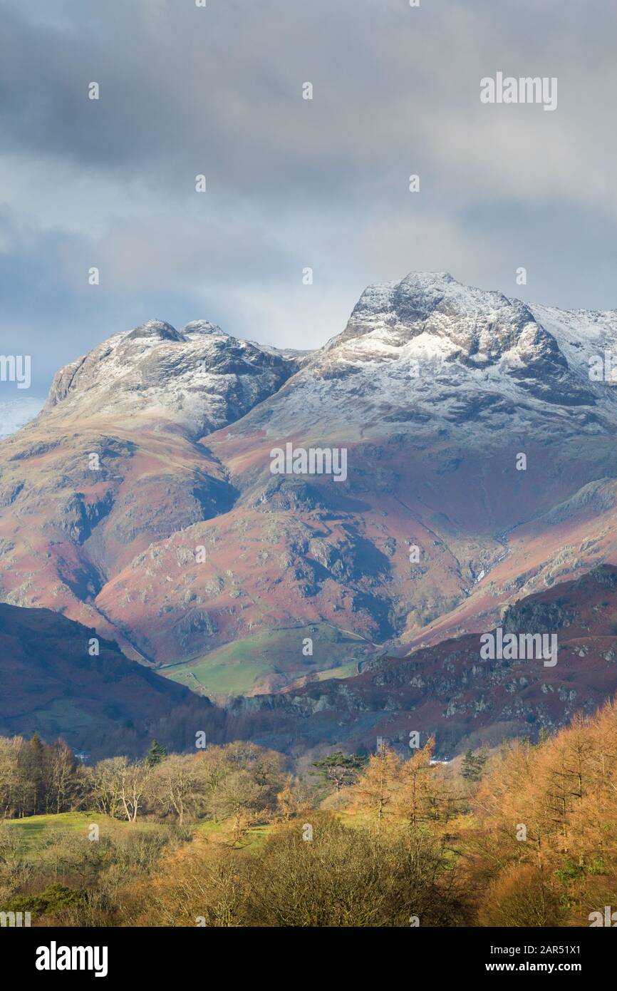 The Langdale Pikes, Great Langdale, with a dusting of snow on a winter's day with patches of cloud and light in the English Lake District Stock Photo