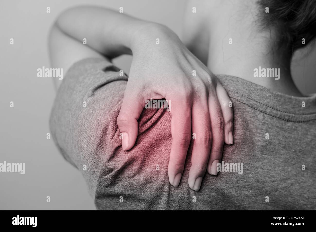 Woman with shoulder pain. Young woman with pain in shoulder. Suffering from pain in shoulder of woman. Stock Photo