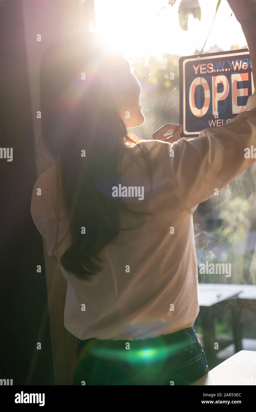 Rear view of Young adult female owner close her cafe coffee shop with close notice board at cafe window Stock Photo