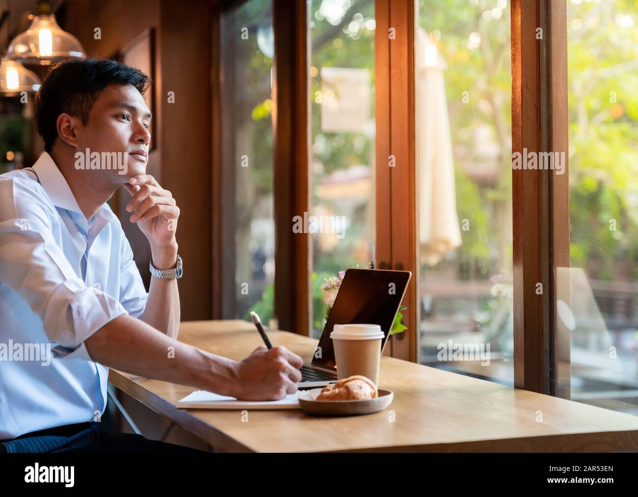 Focused asian college student working with laptop in cafe preparing for test or exam. Stock Photo