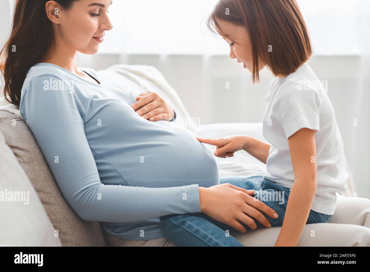 Little kid observing pregnant mummy big belly Stock Photo - Alamy