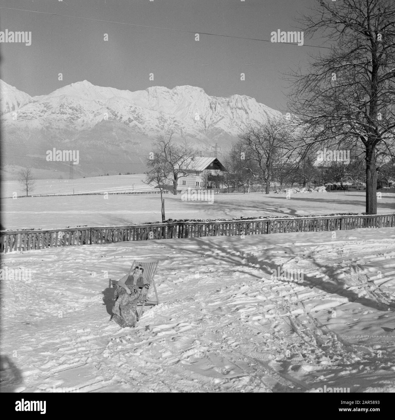 Winter in Tyrol  Hilde Eschen lies sunbathing in the snow with in the background the Karwendel Mountains Date: January 1960 Location: Austria, Sistrans, Tyrol Keywords: mountains, villages, landscapes, snow, holiday, winter Personal name: Echen, Hilde Stock Photo