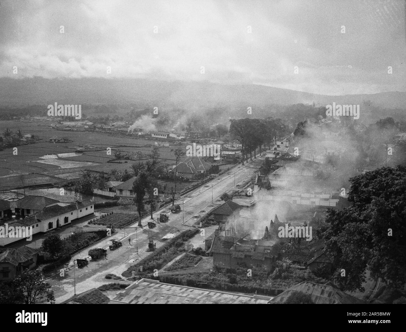 Proceeding to Fort de Kock from Padang Pandjang  In the early morning of December 22nd, 1948 Dutch soldiers moved along the road Padang-Pandjang, towards Fort de - Kock. - Yeah. At a quarter to eight, the first armored cars entered the Republican capital of Sumatra. Except for barriers on the road, the troops encountered virtually no resistance. [Column moves into the city. Burning buildings everywhere] Annotation: Photo taken from the Jam Gedang (Great Clock Tower) Date: 22 December 1948 Location: Bukittinggi, Indonesia, Dutch East Indies, Sumatra Stock Photo