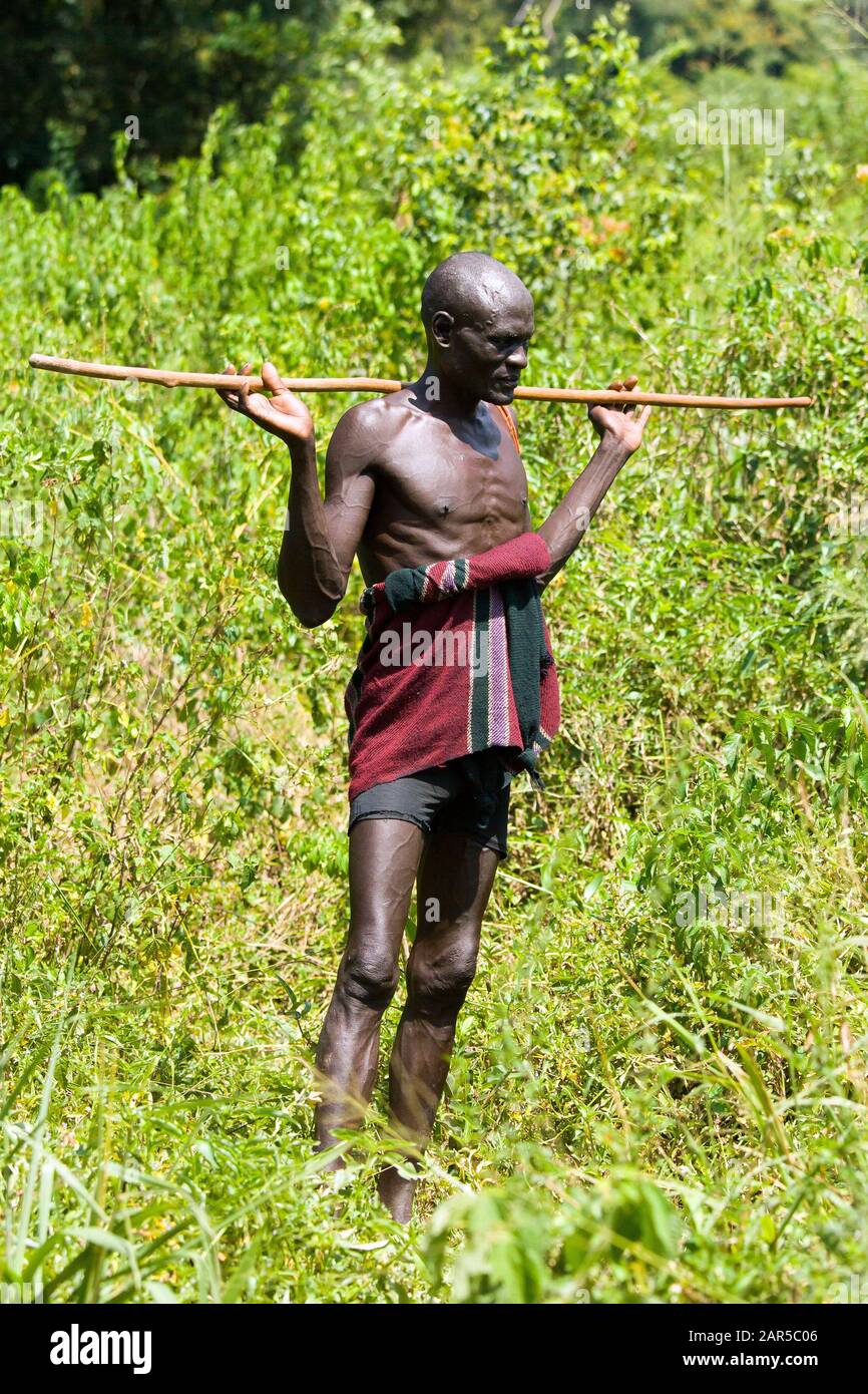 Mursi herder standing in a bush. The Mursi (or Murzu) are a Sub-Saharan African nomadic cattle herder tribe located in the Omo valley in southwestern Stock Photo