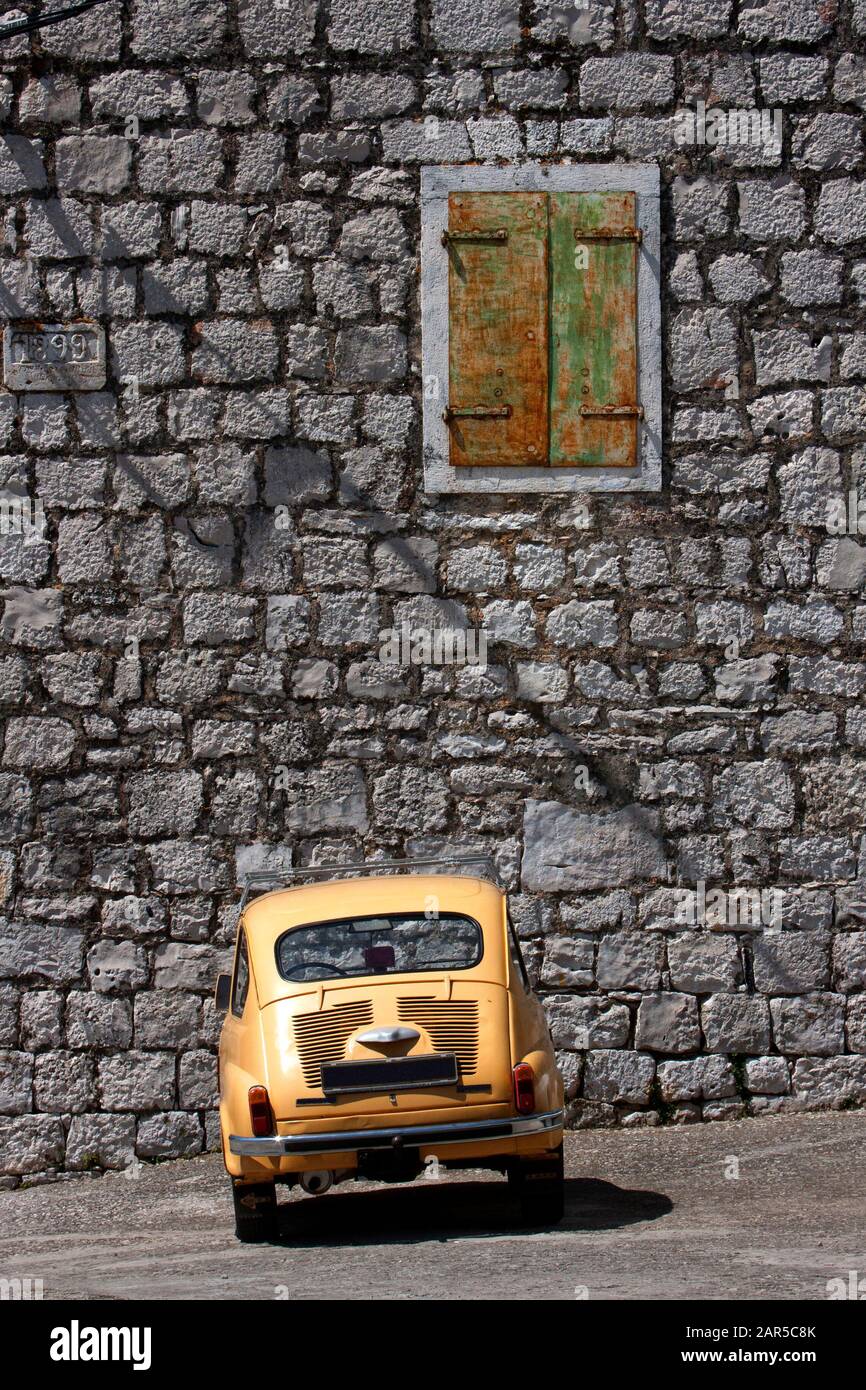 Donje Selo, island Solta, Croatia, orange old car Zastava 750 in front of stone facade Stock Photo