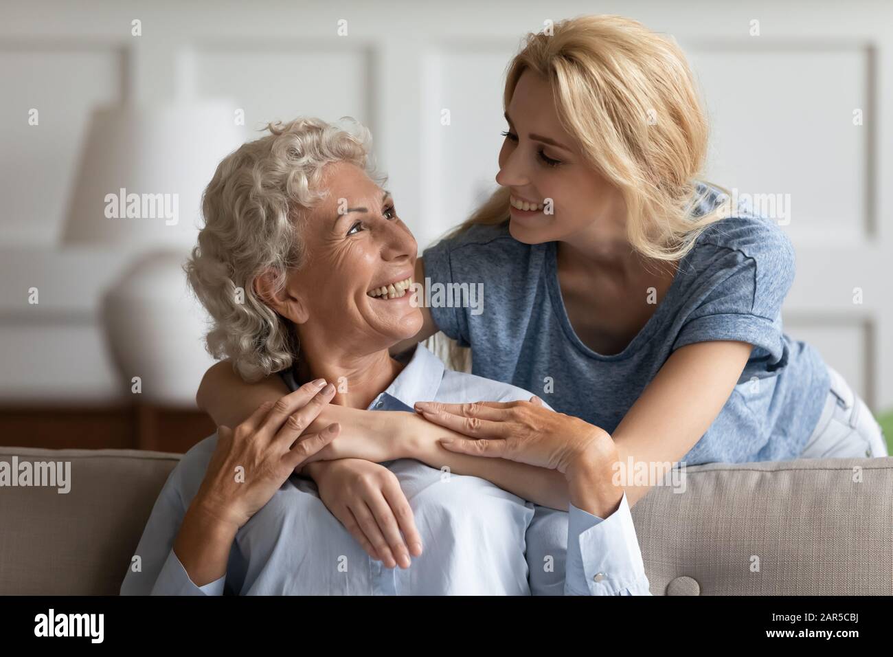 Smiling middle aged pleasant woman looking at attractive grownup daughter. Stock Photo
