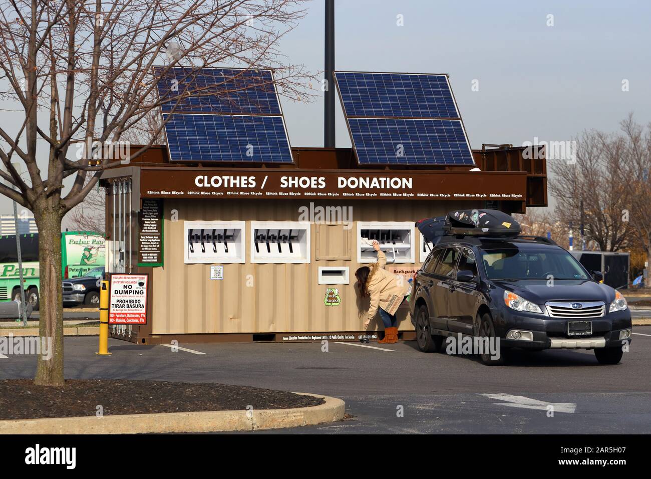 A person depositing items into a Green Education Foundation donation station equipped with solar panels at a shopping mall in Philadelphia, PA. Stock Photo