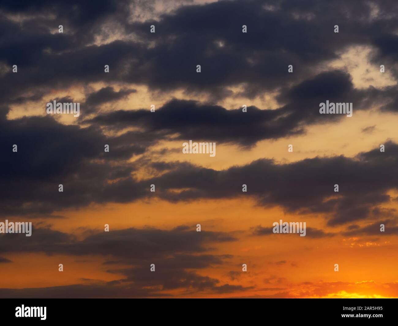 Dark gray clouds on a red sunset sky Stock Photo