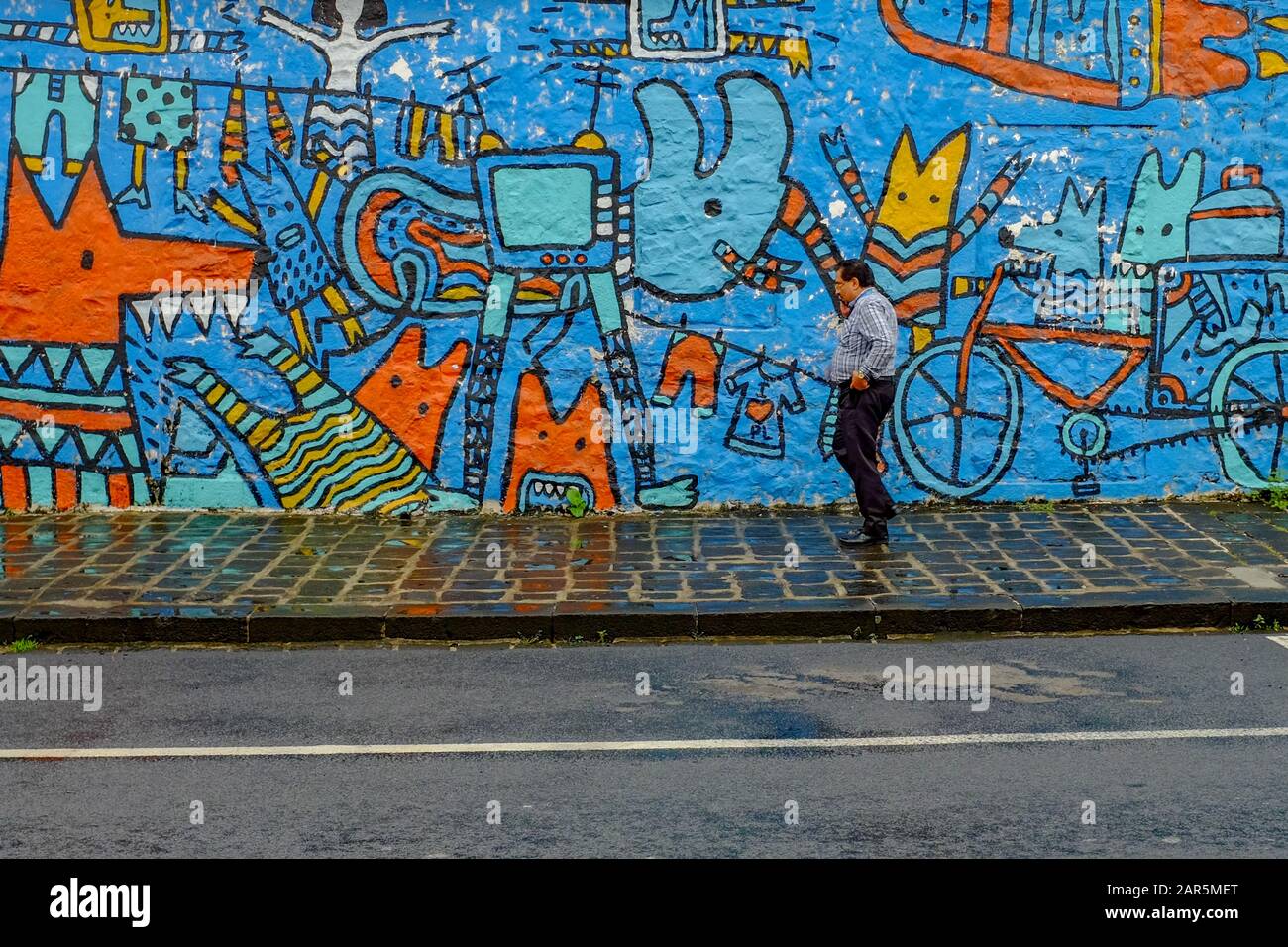 A man walks past a wall covered in colourful murals in Port Louis, the capital of Mauritius. Stock Photo