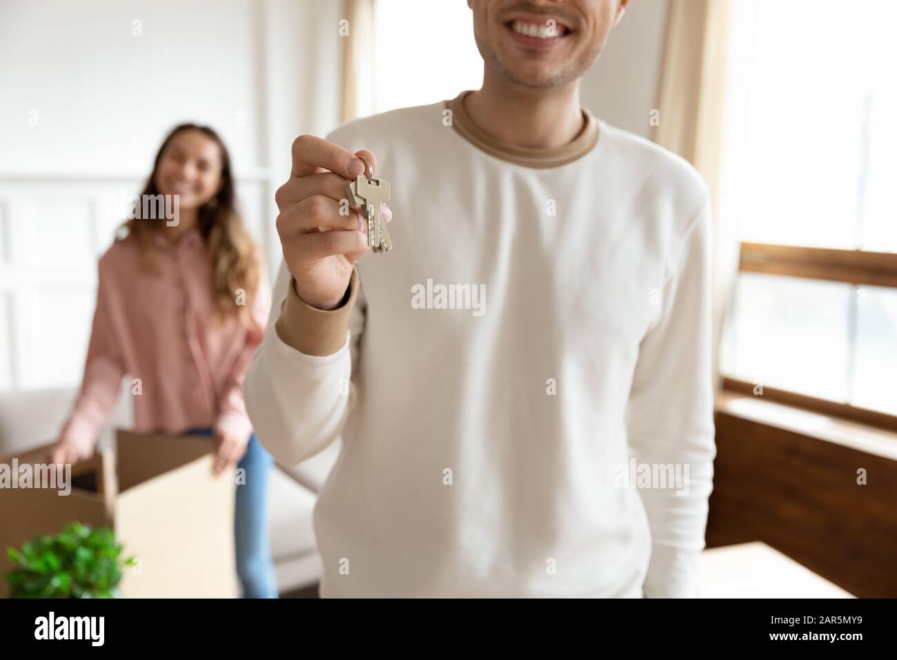 Overjoyed young husband show house keys moving together with wife Stock Photo