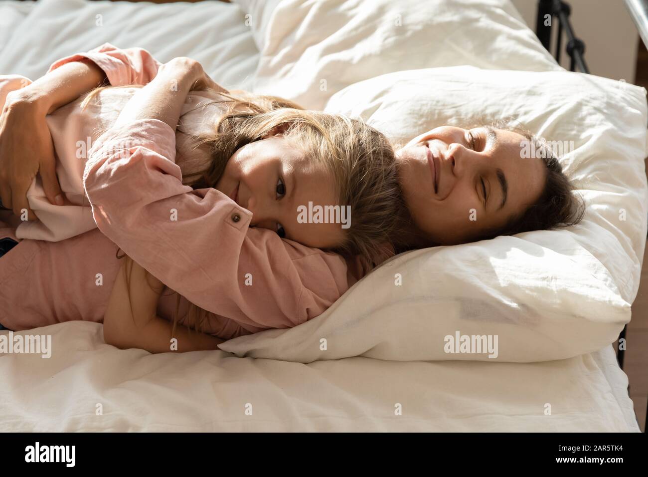 Loving mum cuddle relaxing in bed with little daughter Stock Photo