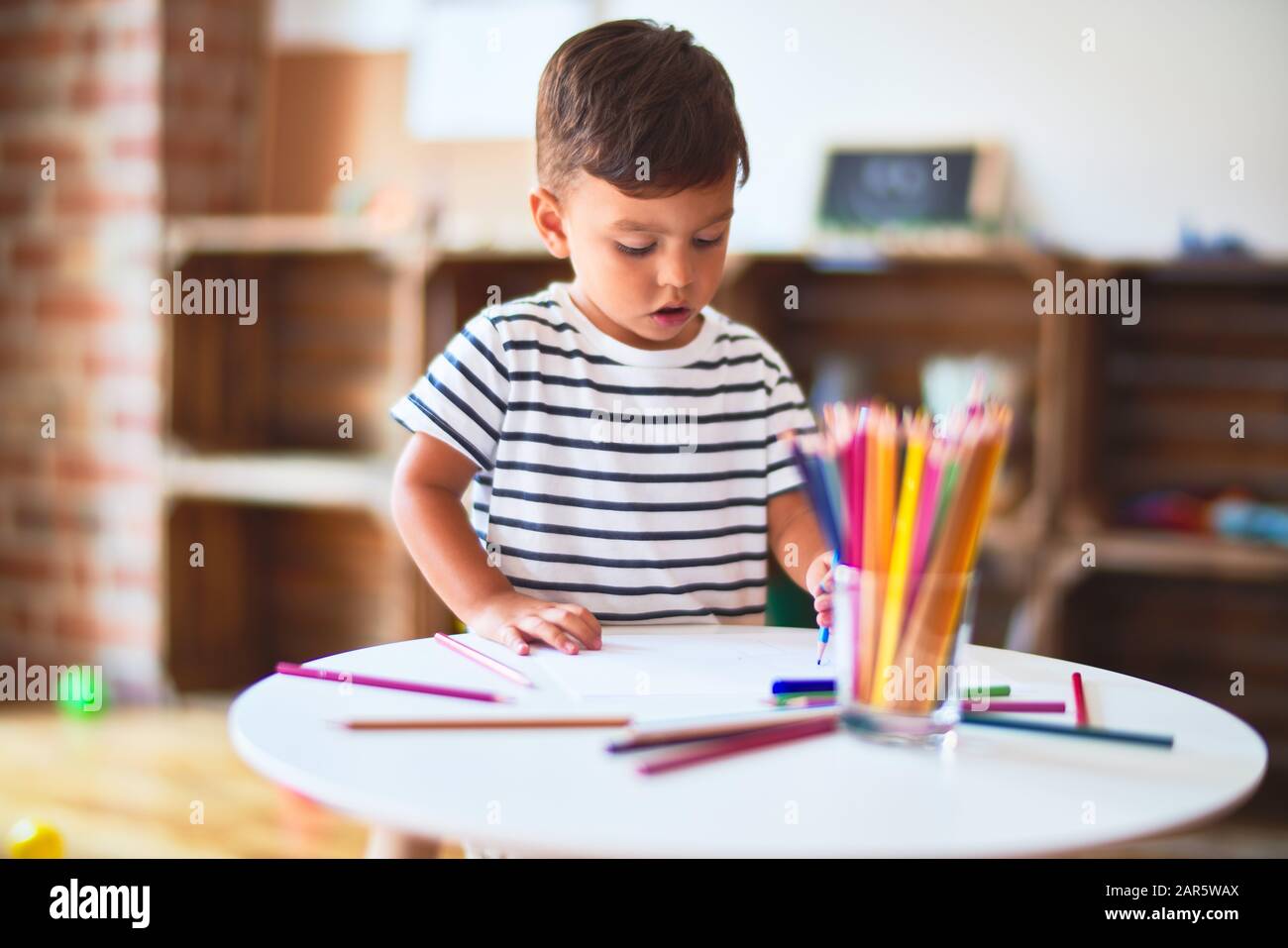 Beautiful toddler boy drawing cute draw using colored pencils at ...