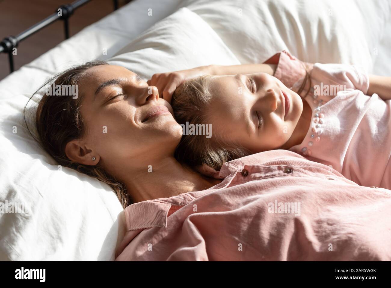 Happy mom relaxing sleeping with little daughter in bed Stock Photo