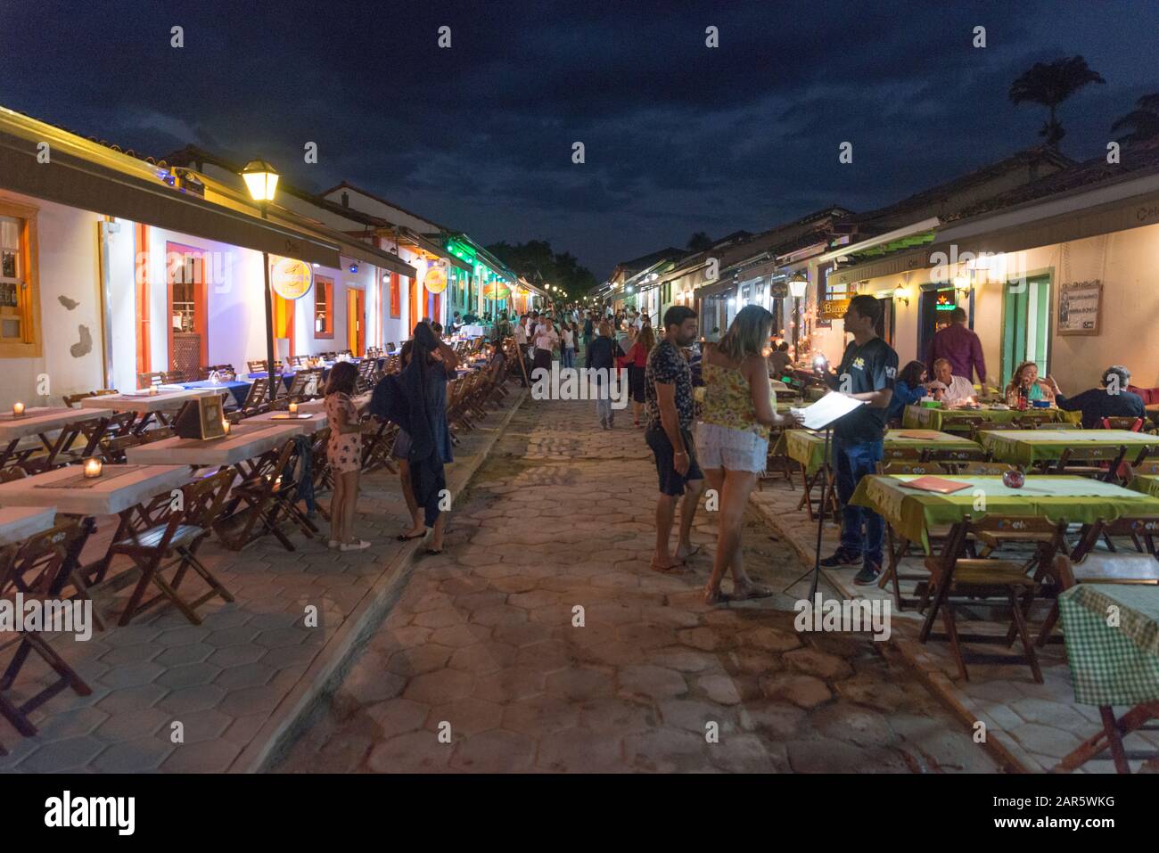 Pirenópolis, Goiás, Brazil. 18th July 2019. Nightlife at Rua do Lazer in Pirenópolis. Tourists looking at menu of a restaurant in the evening. Stock Photo
