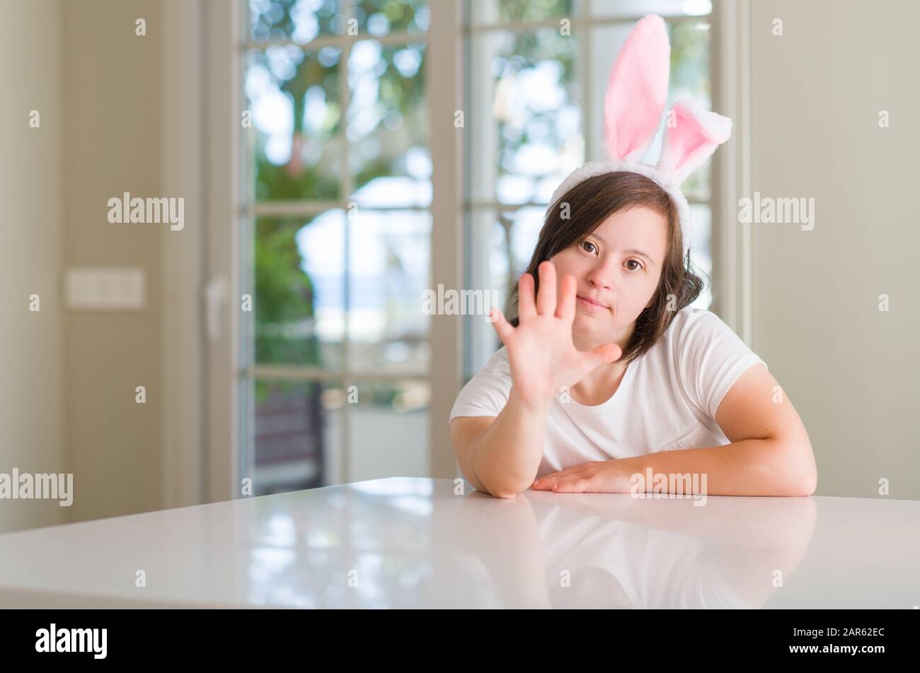 Down syndrome woman at home wearing easter rabbit ears with open hand ...