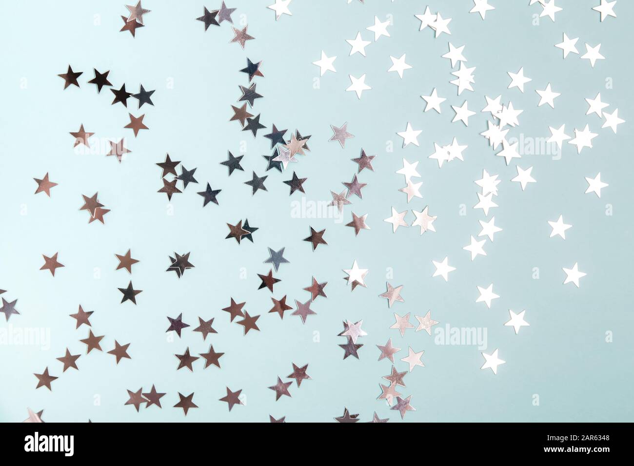 Star shaped silver sequins over blue background. Stock Photo