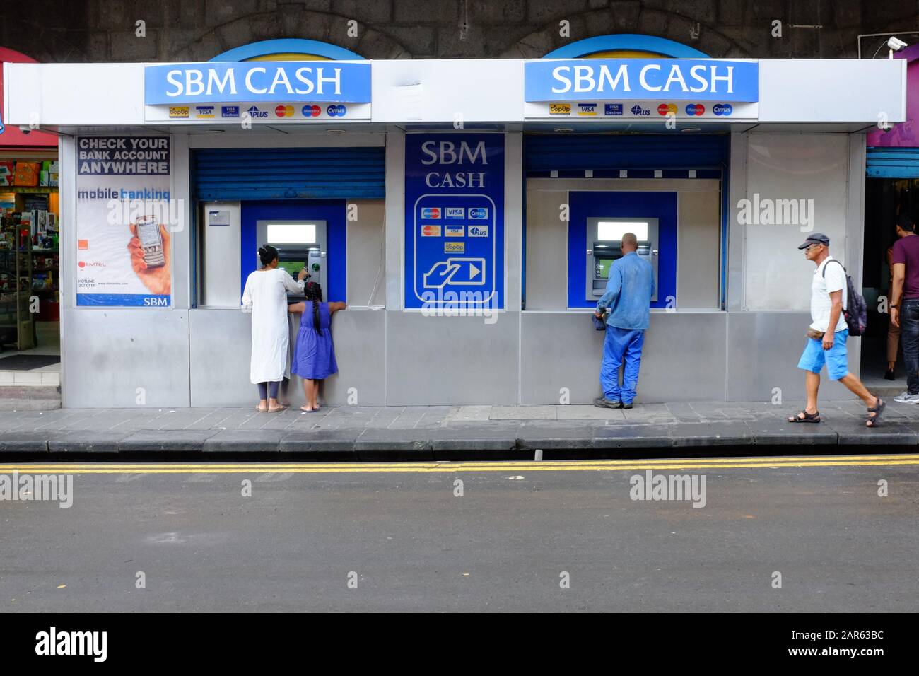Customers use ATM machines to do their banking at an SBM Bank cash point in Port Louis, Mauritius. Stock Photo