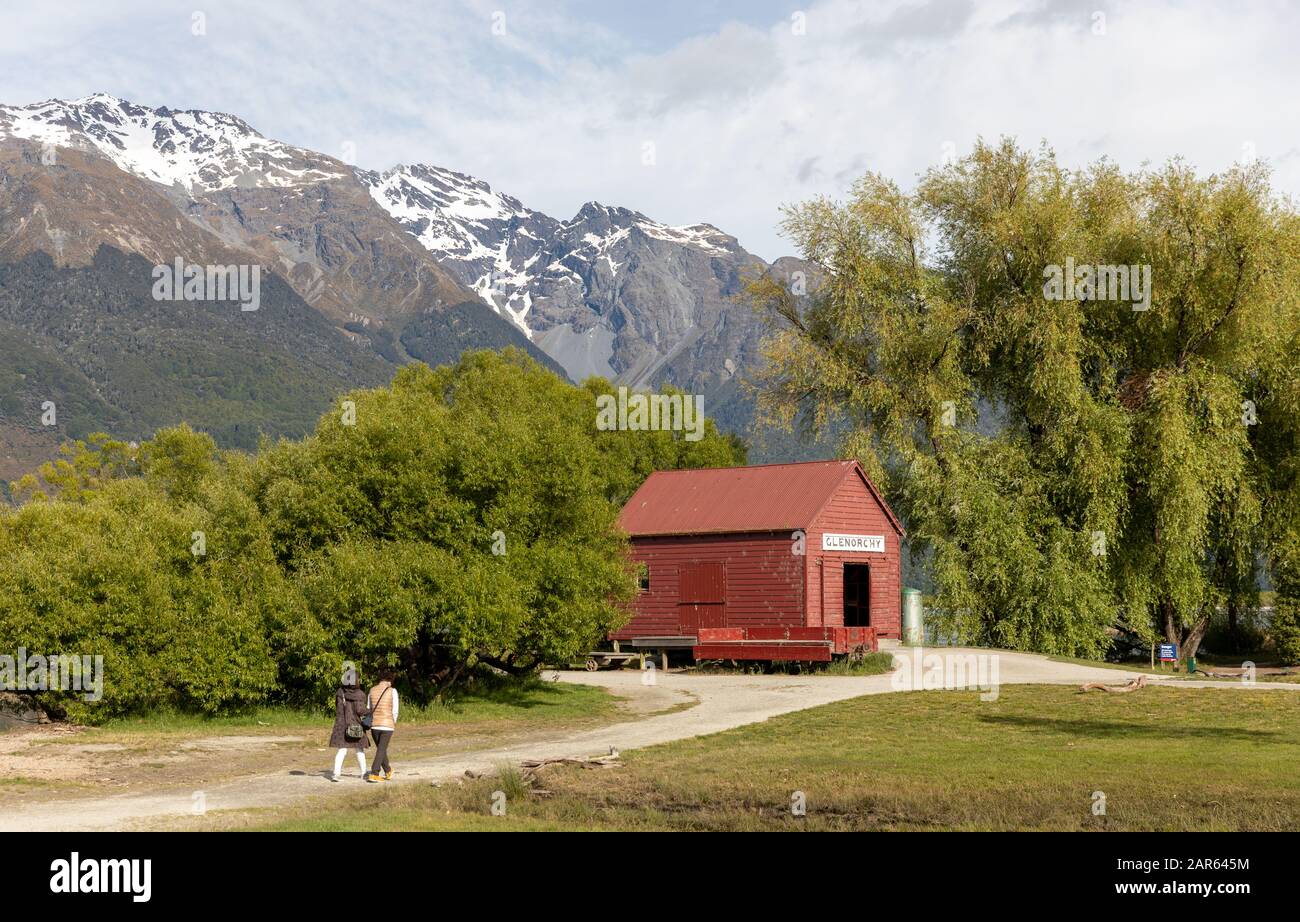 The red boat shed of Glenorchy, New Zealand in summer with two tourists in the distance Stock Photo