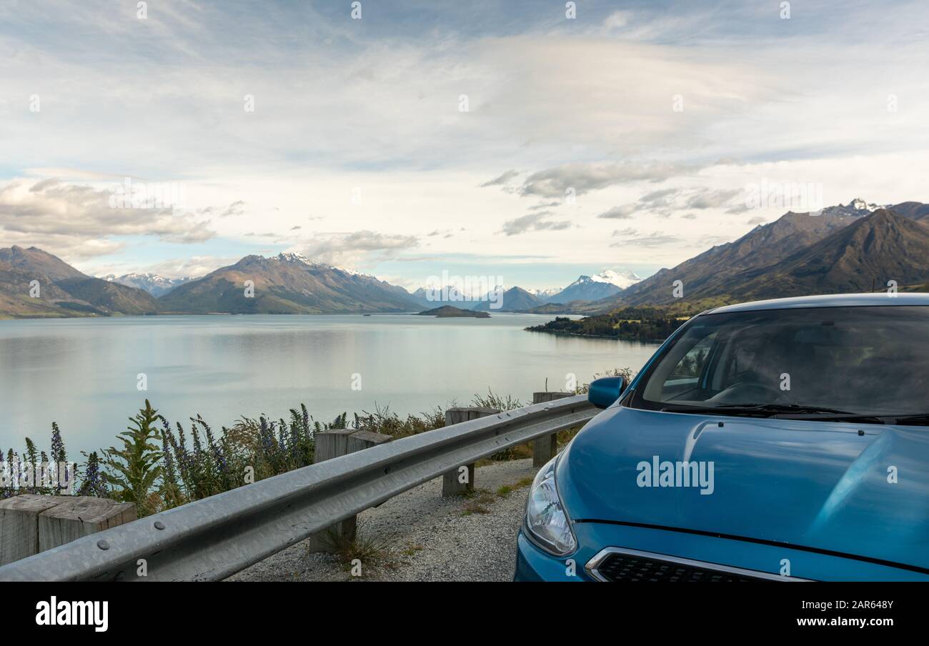 A blue car parked at a scenic overlook at Lake Wakatipu, New Zealand Stock Photo