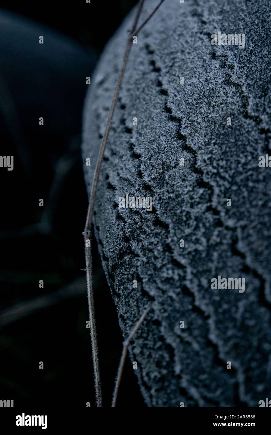 Old dumped tires covered in frost. Rubbish illegally left in a farmers field. Fly tipping is a UK rural crime. Close up of rubbish. Stock Photo