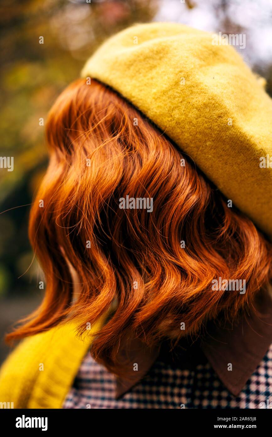 A beautiful red-haired woman with a curly hairstyle walking in the park Stock Photo