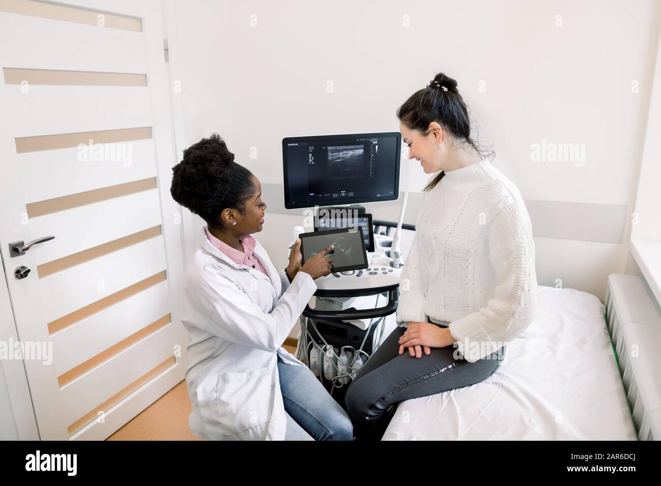 African female doctor gynecologist showing echo ultrasound photo on digital  tablet to happy pregnant woman in modern medical office Stock Photo - Alamy