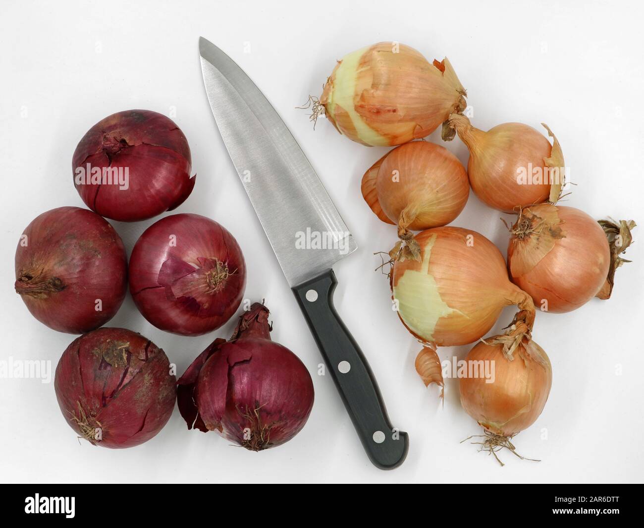 top view of red and yellow onions with kitchen knife in the middle on white background Stock Photo