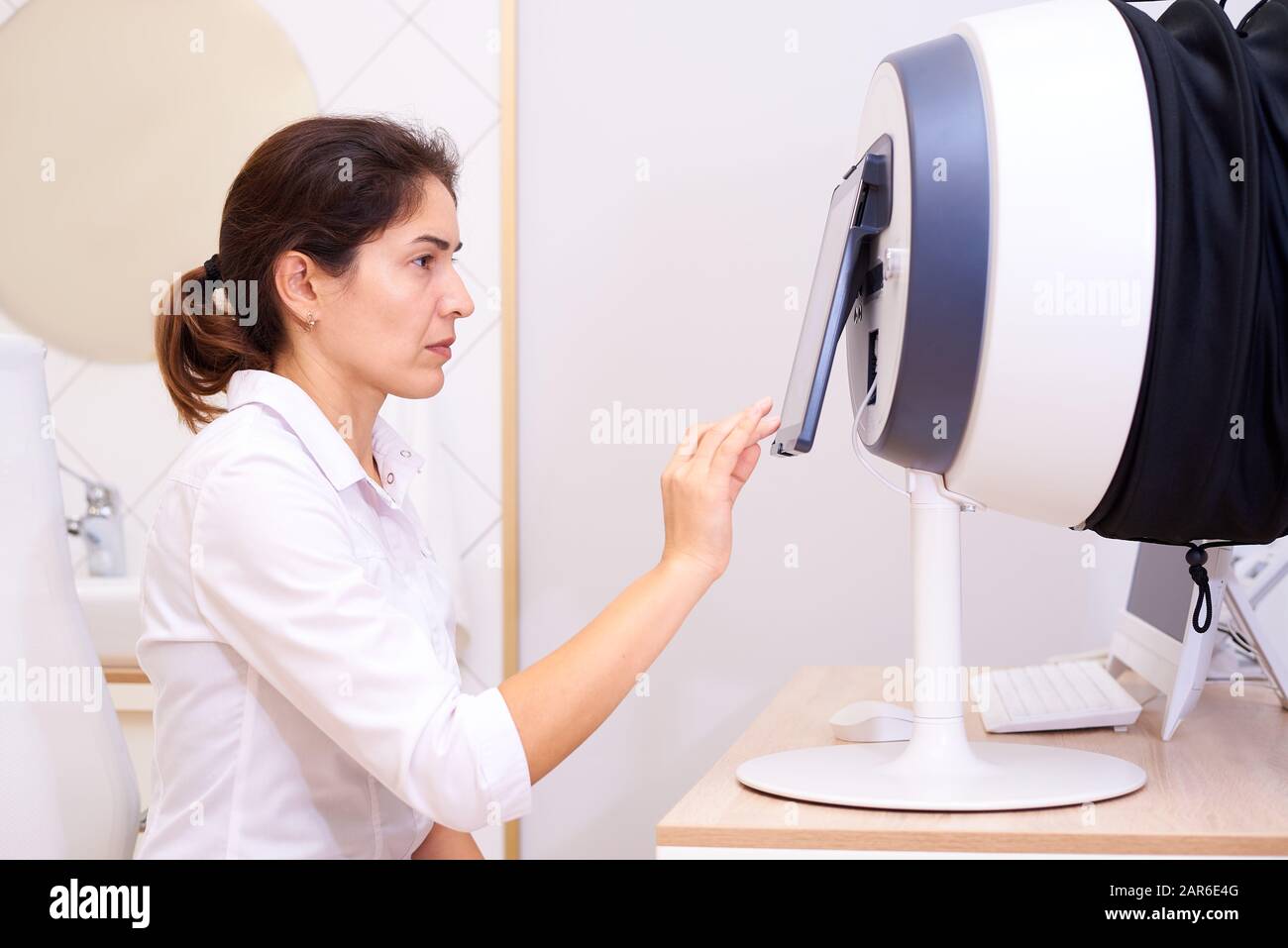 Doctor with equipment for the diagnosis of facial skin for dermatology and cosmetology. Stock Photo