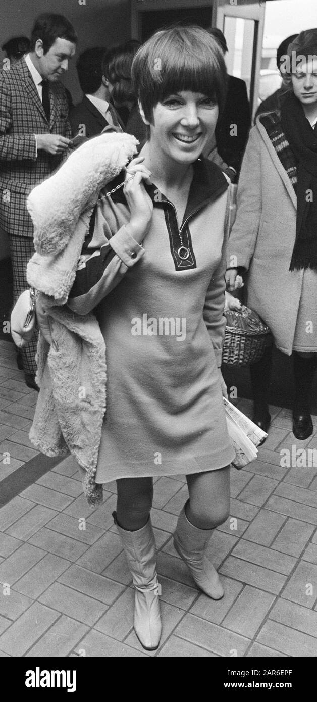 Mary Quant wearing a mini dress of her own design, with a sheepskin coat and bag thrown over her shoulder, and wearing go-go boots.; Stock Photo