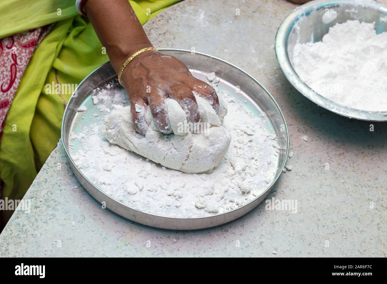 an Indian woman scooping flour/rice powder for making breads Stock Photo