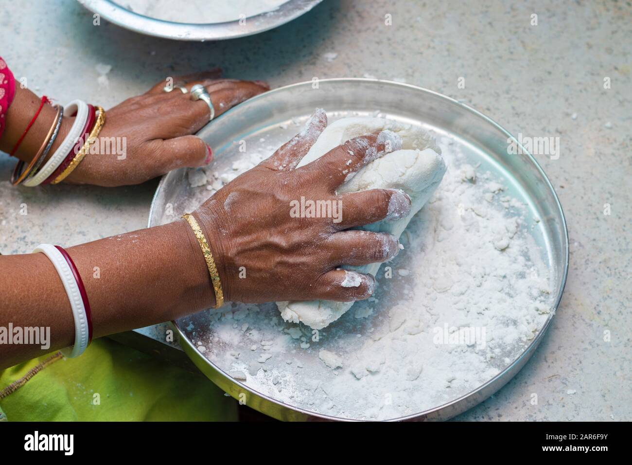 an Indian woman scooping flour/rice powder for making breads Stock Photo