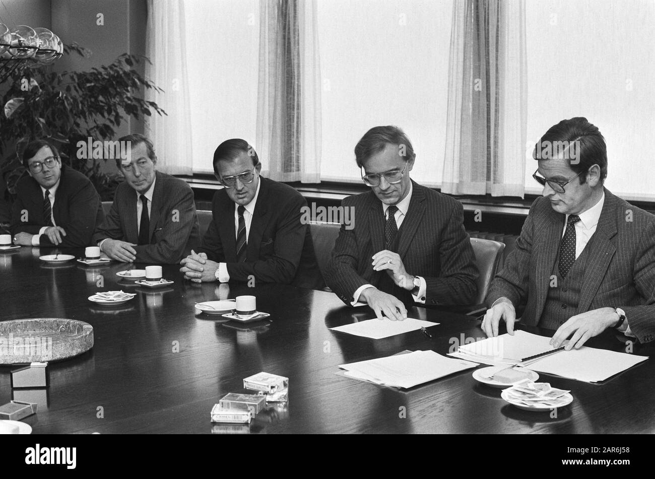 Minister Ruding (middle) signed in Rotterdam the founding act of the Postbank  Minister Ruding studies documents Date: 31 December 1985 Location: Rotterdam, Zuid-Holland Keywords: banks, banking, ministers, foundation Personal name: Ruding, Onno Stock Photo