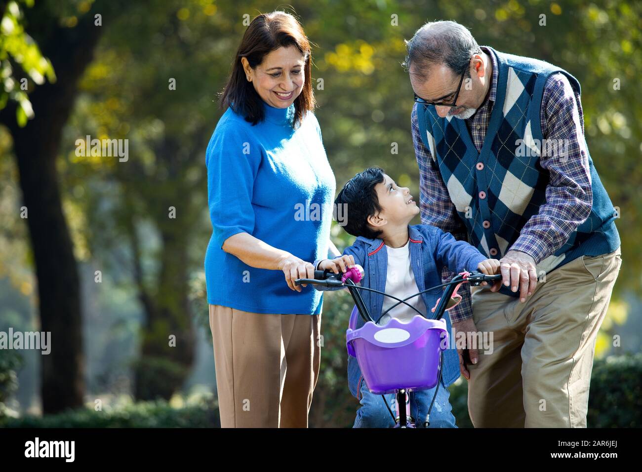 Grandparents with grandson learning to ride bicycle Stock Photo