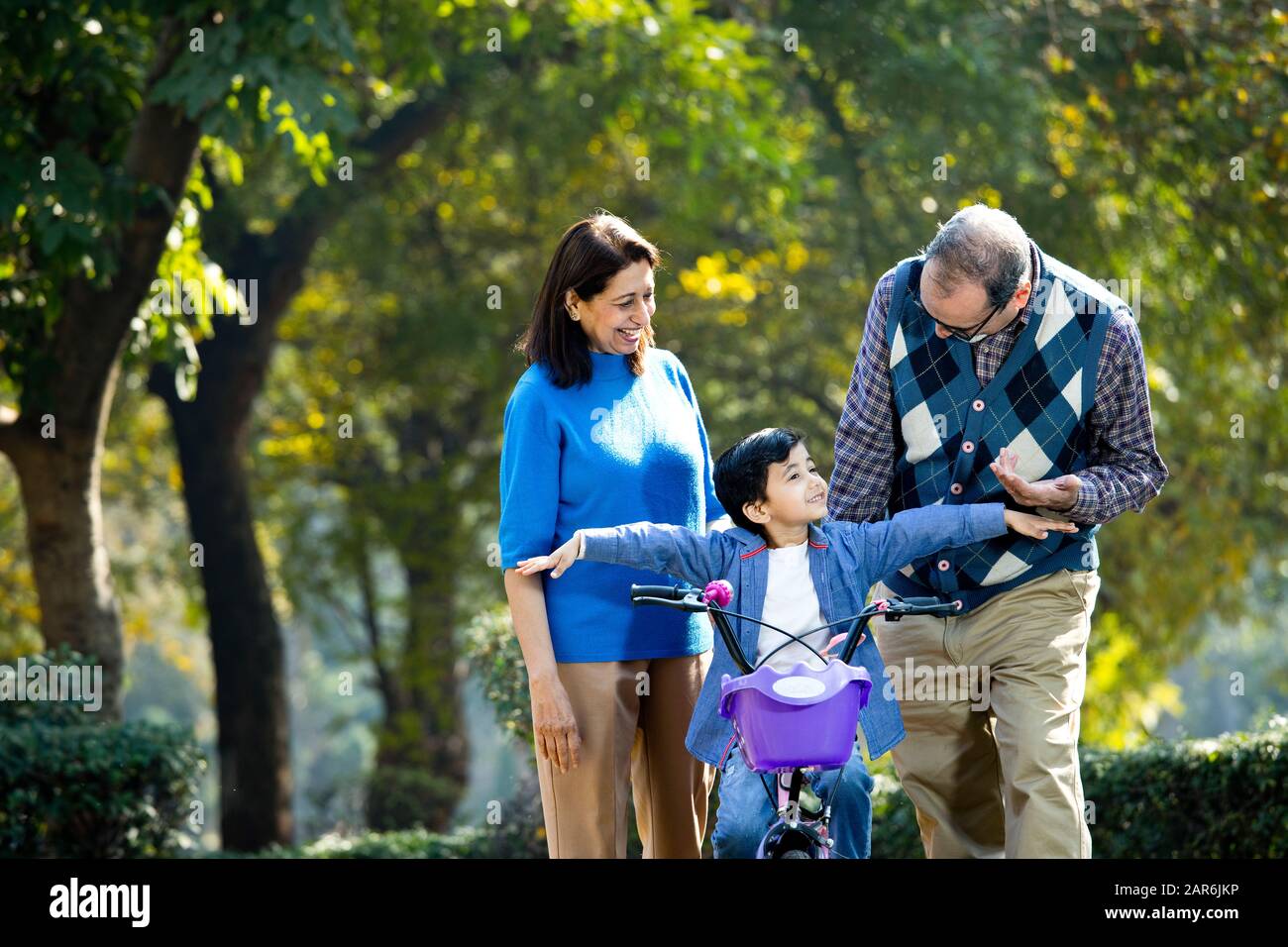Grandparents with grandson learning to ride bicycle Stock Photo
