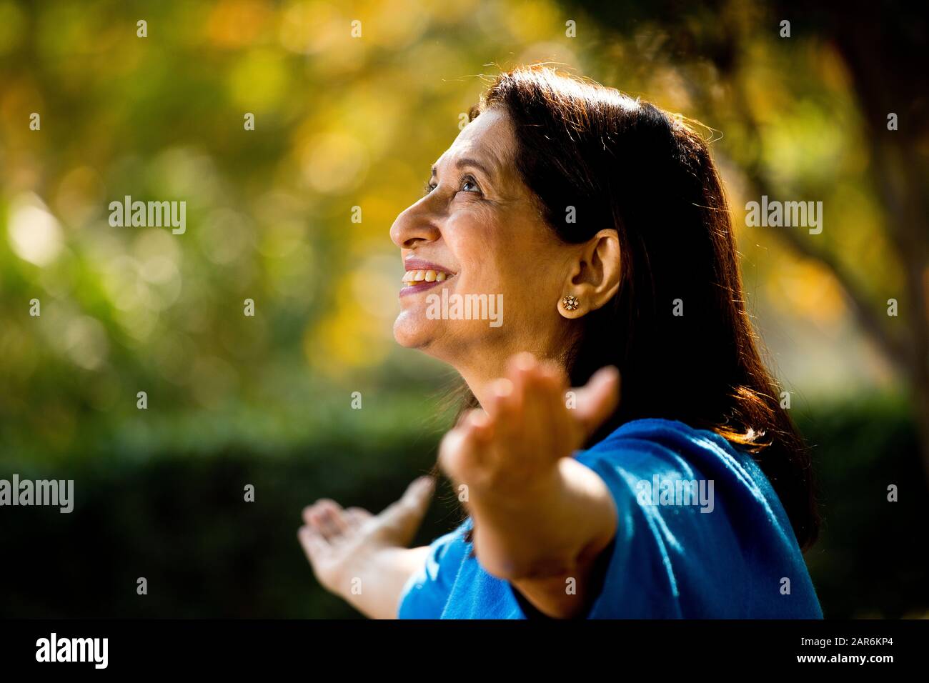 Senior woman with arms outstretched at park Stock Photo