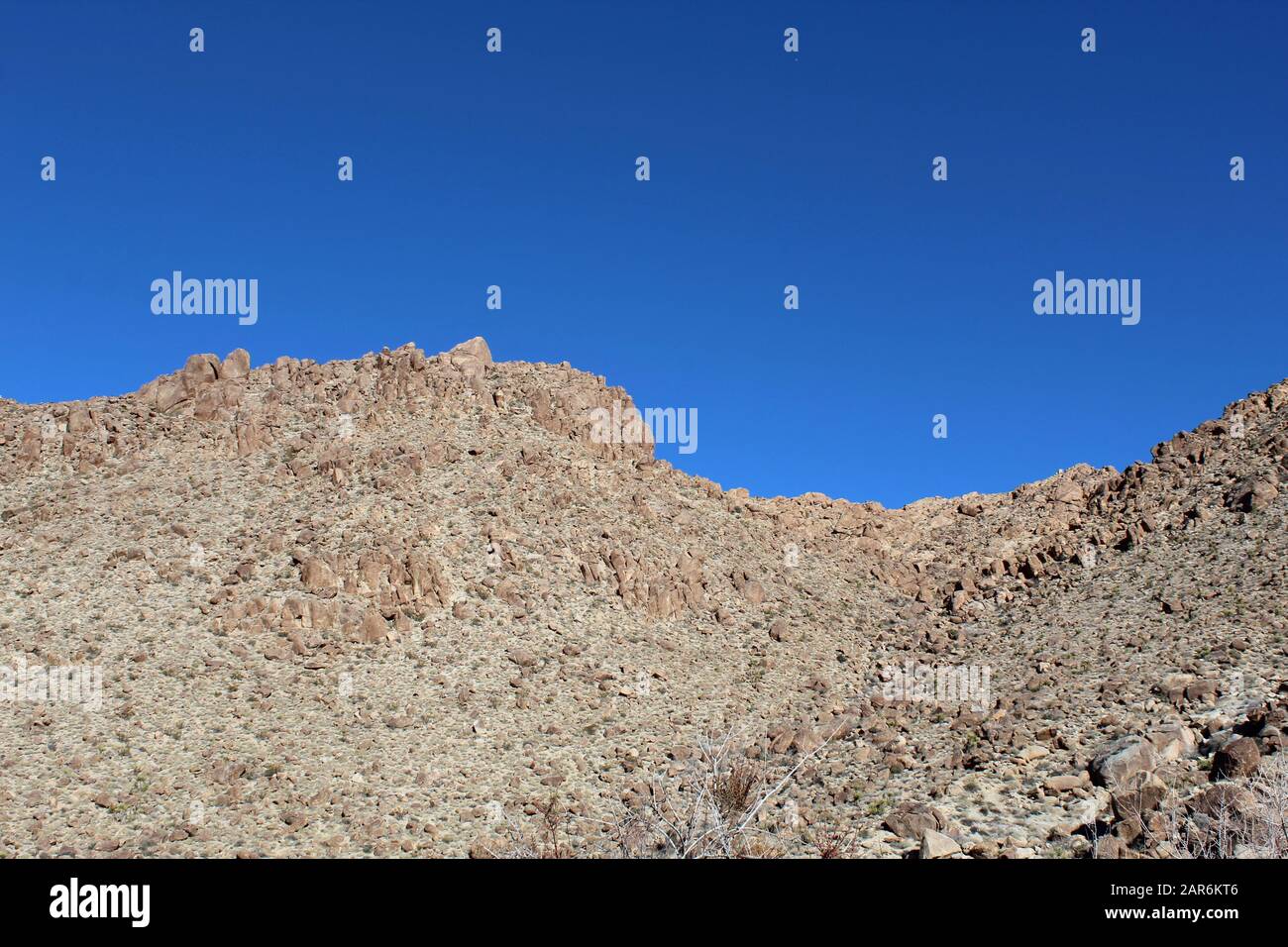 Below the deep blue Southern Mojave Desert sky rises ridges bounding ...