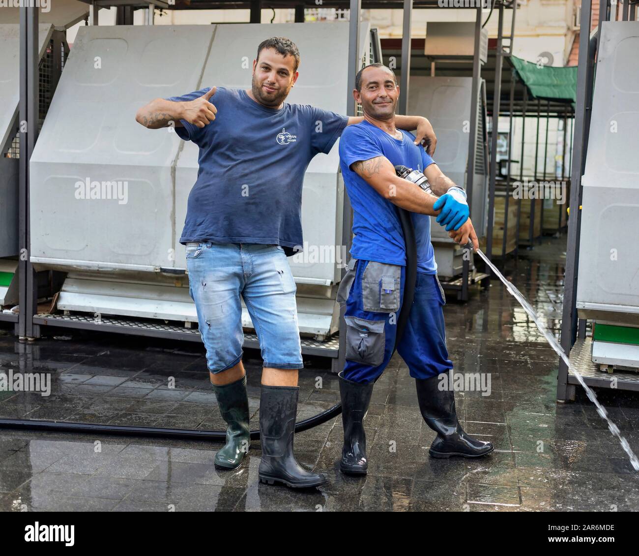 Belgrade, Serbia, Sep 5, 2019: Two workers posing while washing green market floor at the end of the work day Stock Photo